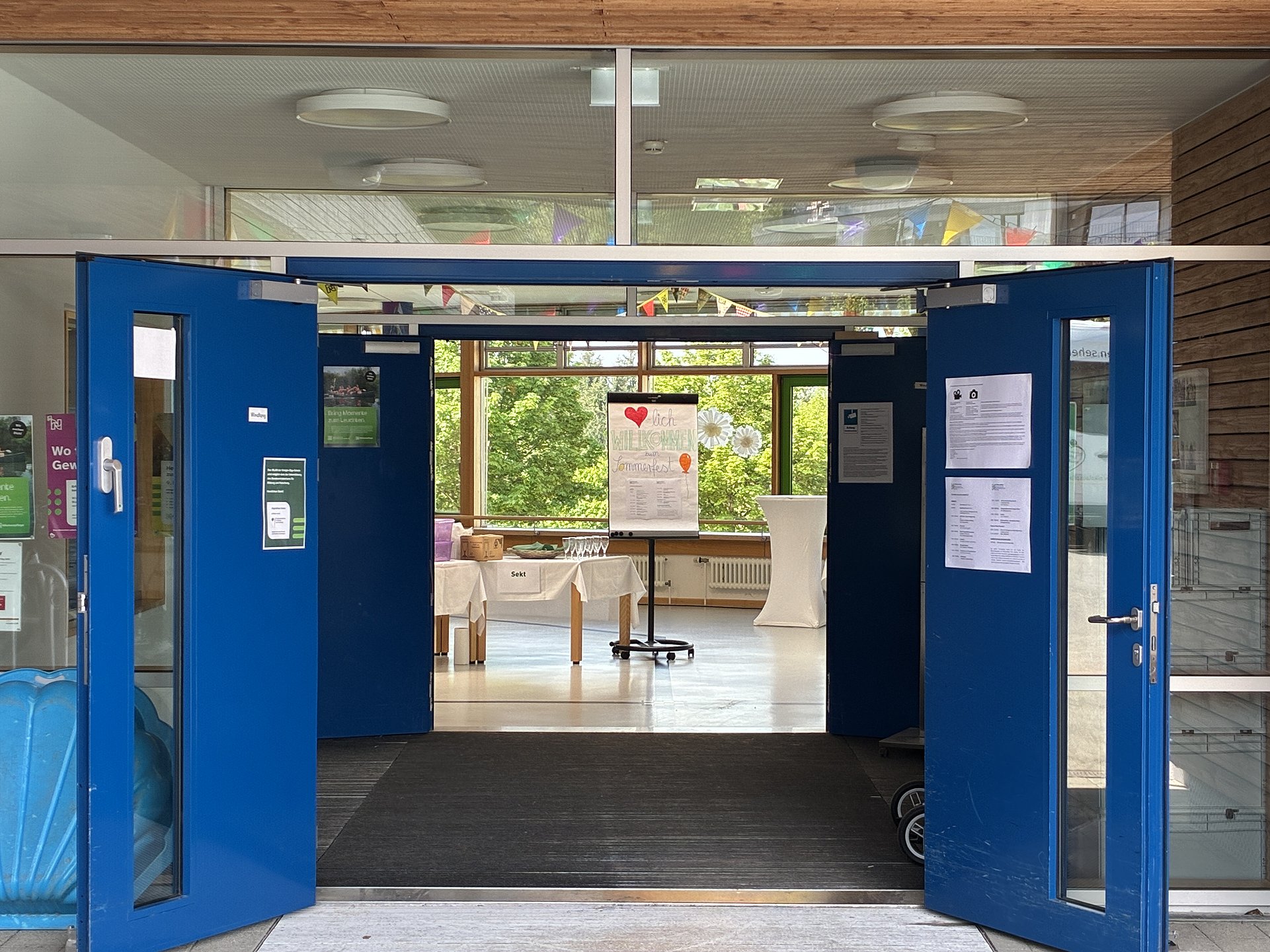 Im Eingang der Königin Olga Schule steht ein Flipchart und gedeckte Tische. Beide Türen des Eingangs stehen weit offen