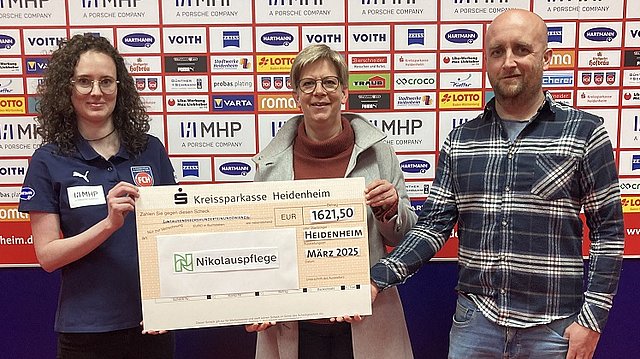 Tatjana Müller vom 1. FC Heidenheim, Gesina Wilfert und Stefan Schiefelbein von der Nikolauspflege in Heidenheim halten den Spendenscheck in der Hand.